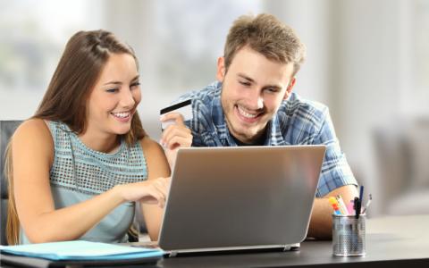 Deux jeunes adultes utilisent ensemble un ordinateur portable dans un environnement lumineux.