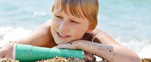 garçon et son bras cassé à la plage