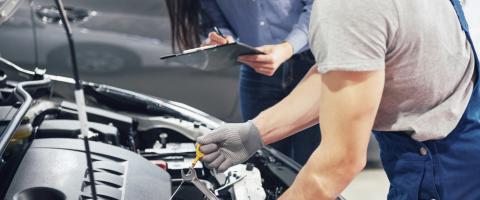Mécanicien travaillant sur une voiture capot ouvert.