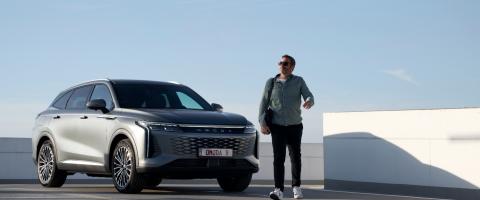 Un homme passe devant une Omoda 9 vue de 3/4 avant