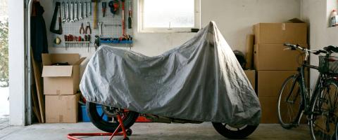 Moto avec housse respirante sur béquille de stand dans un garage pendant l'hivernage.