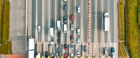 Télépéage: Vue aérienne sur une autoroute à péage où de nombreuses voitures font la queue à un poste de péage.