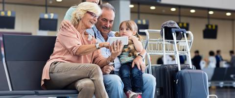 vliegvakantie - grootouders en kleindkinderen met koffers in de luchthaven