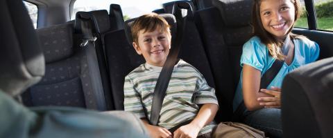 twee lachende kinderen op de achterbank van een auto