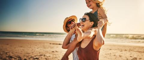 ouders met kind op de schouder op een strand