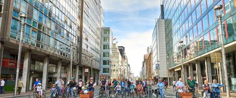 brede laan met hoogbouw - zonder auto's maar met voetgangers en fietsers op het wegdek