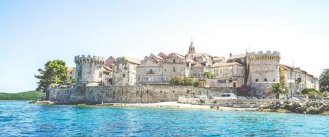 foto van een grijs betonnen gebouw nabij een waterpartij (Korčula)