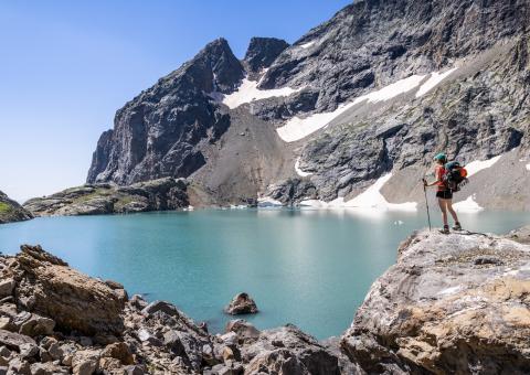 Foto van een meisje in short nabij een blauw meer nabij een bergtop in de Franse Alpen.
