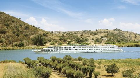 Slow cruise: schip op een rivier door een desolaat en dor landschap