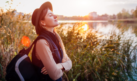 Balades d'automne: femme de profil avec un sac à dos, l'air serein au bord d'une rivière. en Belgique