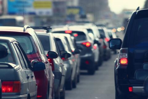 Une longue file de voitures est arrêtée dans un embouteillage sur une route urbaine animée.