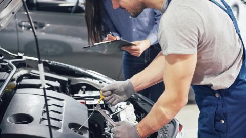 Mécanicien travaillant sur une voiture capot ouvert.