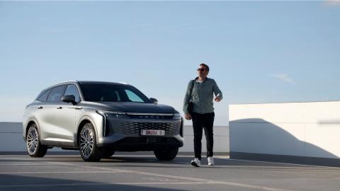 Un homme passe devant une Omoda 9 vue de 3/4 avant