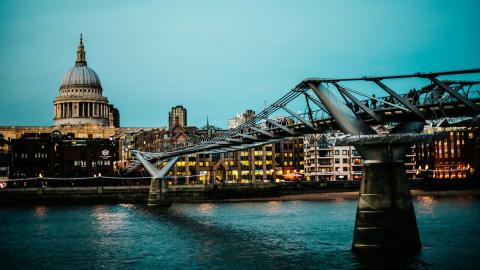 Londres, Passerelle piétonne au-dessus de la Tamise menant à un bâtiment en forme de dôme au crépuscule.