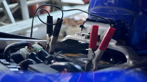 Druppellader met klemmen aangesloten op motorbatterij onder het zadel