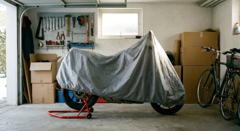 Moto avec housse respirante sur béquille de stand dans un garage pendant l'hivernage.