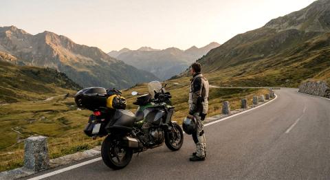 Motorrijder geniet van uitzicht over Alpen bergpas tijdens motorreis met beladen motorfiets