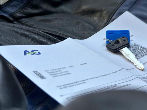 Motorverzekering documenten van AG Insurance met groene kaart en motorsleutel op leren motorjas