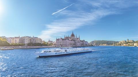 CroisiEurope schip op brede rivier in een stad met gigantisch paleis op de achtergrond