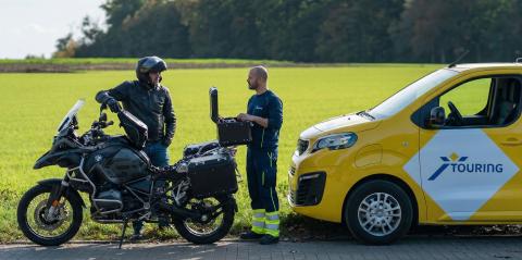 Touring wegenwachter arriveert bij motorrijder met pech onderweg en opent gereedschapskist naast BMW GS motor