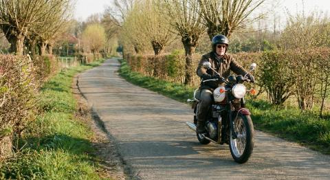 Motorrijder rijdt zorgeloos over landweg in het voorjaar