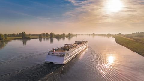 Riviercruiseschip bij zonsondergang, mist op het water. CroisiEurope