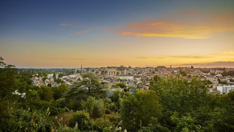 panorama sur une vieille ville avec de nombreuses tours et un ciel bleu orangé.