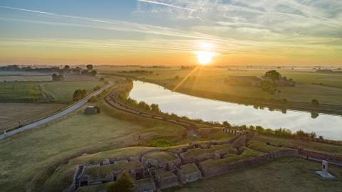Rivier met loopgraven op de voorgrond bij zonsondergang