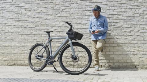 Un homme est adossé contre un mur et regarde son vélo de ville