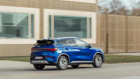 BYD Atto 3 Evo bleu vu de profil, en circulation devant un bâtiment moderne.
