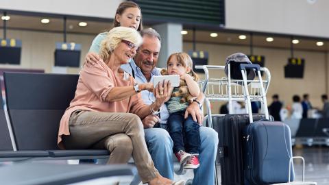 vliegvakantie - grootouders en kleindkinderen met koffers in de luchthaven