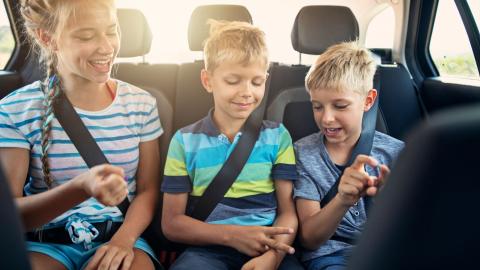 Des enfants, loin des écrans, jouent à des jeux sur la banquette arrière d'une voiture.