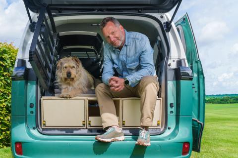 man zit naast hond in de kofferbak van een auto