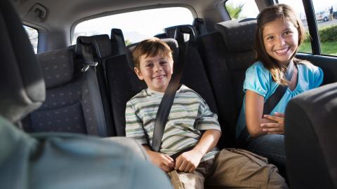 twee lachende kinderen op de achterbank van een auto