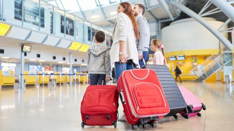 koppel met kind in de luchthaven met bagage in de hand