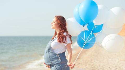vrouw zwanger op strand met ballons
