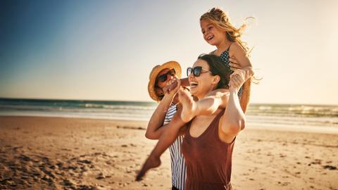 des parents avec un enfant sur les épaules sur une plage.