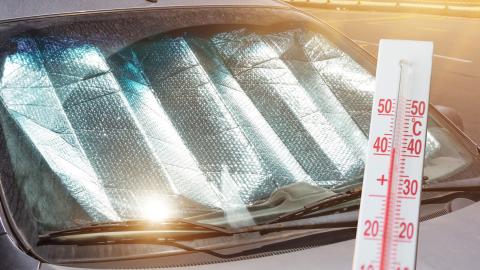 Pare-brise recouvert d'un pare-soleil pendant une canicule, thermomètre à l'avant-plan.