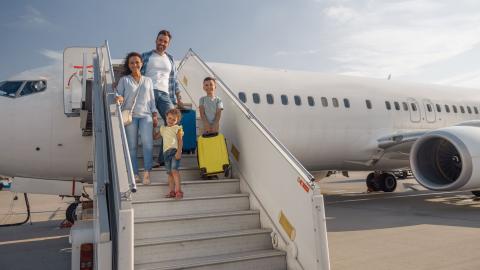 familie met twee kinderen op de trap richting ingang vliegtuig