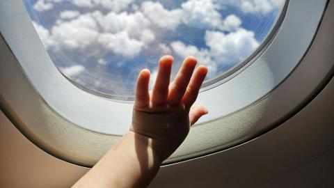 hand van een baby op het raam van een vliegtuig