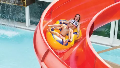 Parc aquatique: deux enfants dévalant un toboggan sur des bouées.