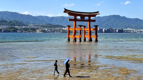 rode torii in het water met mensen op de voorgrond in Japan