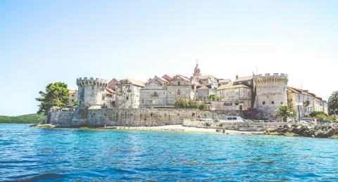 foto van een grijs betonnen gebouw nabij een waterpartij (Korčula)