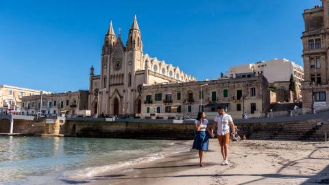 twee mensen op een strand, statig gebouw met twee torens op achtergrond
