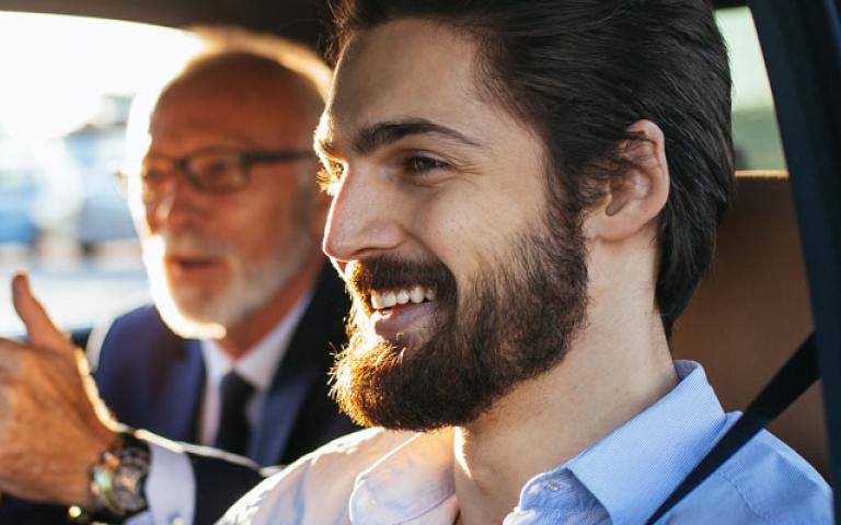 two men sitting in a car smiling