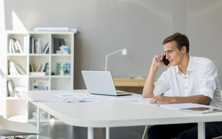 a man making a call looking at a laptop
