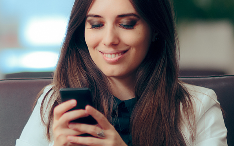 Woman using her phone, smiling at the screen
