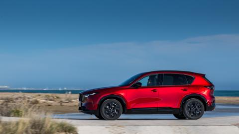 Mazda CX-5 rouge de profil en bord de mer, ciel bleu.